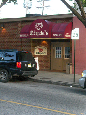Photo shows a one-story brick building with a sign above some double doors saying 'Obrycki's'.